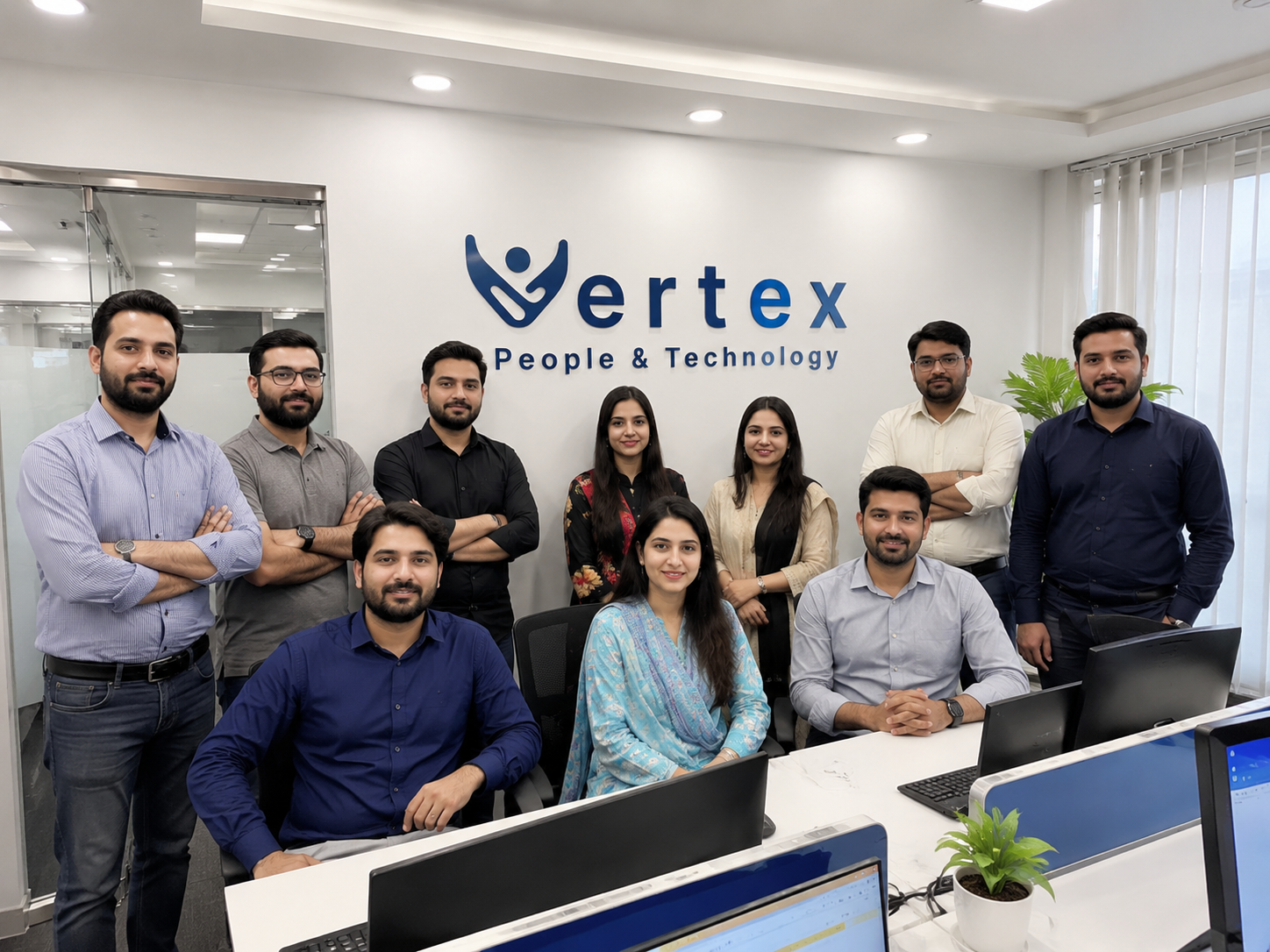 The Vertex team at the office, standing together beneath the Vertex People & Technology sign